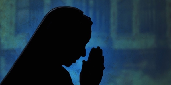 silhouette of a nun praying