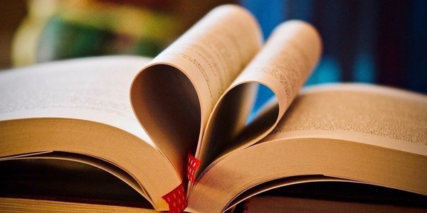an open book with pages folded into each other to resemble a heart