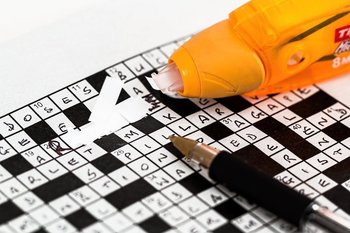 crossword puzzle with pen and white-out pen for corrections
