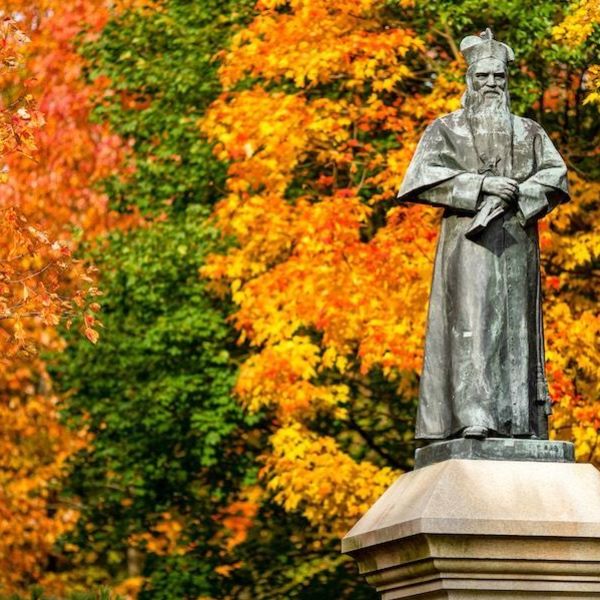 statue of Rev. Edward Sorin, C.S.C., Notre Dame's founder, on  Main Quad in the fall with brightly colored leaves in the background