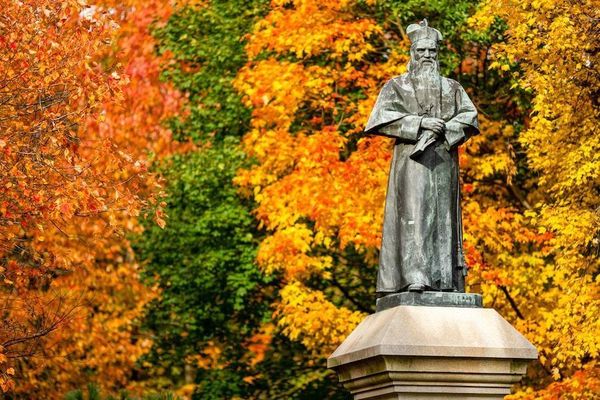statue of Rev. Edward Sorin, C.S.C., Notre Dame's founder, on  Main Quad in the fall with brightly colored leaves in the background